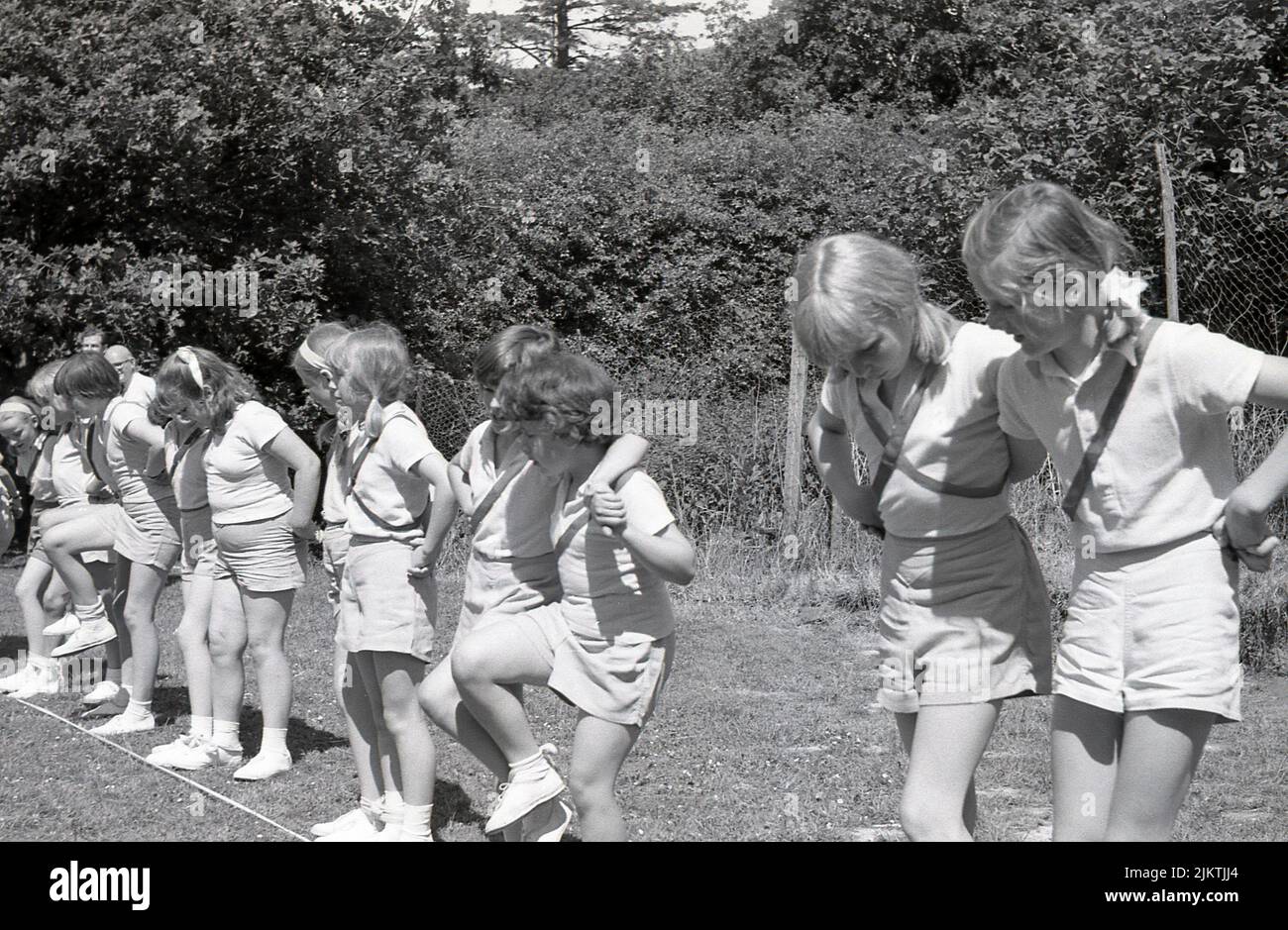 1966, histórico, deportes escolares, fuera en un campo, niñas en ropa de gimnasio alineados para el inicio de la carrera de tres patas, Inglaterra, Reino Unido. Foto de stock