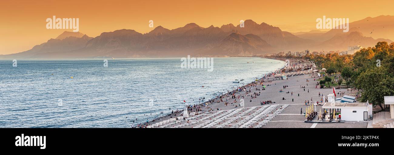 Vista panorámica al atardecer de la pintoresca y popular playa Konyaalti en la ciudad turística de Antalya. Majestuosas montañas con neblina en el fondo. Vacaciones y vacaciones Foto de stock