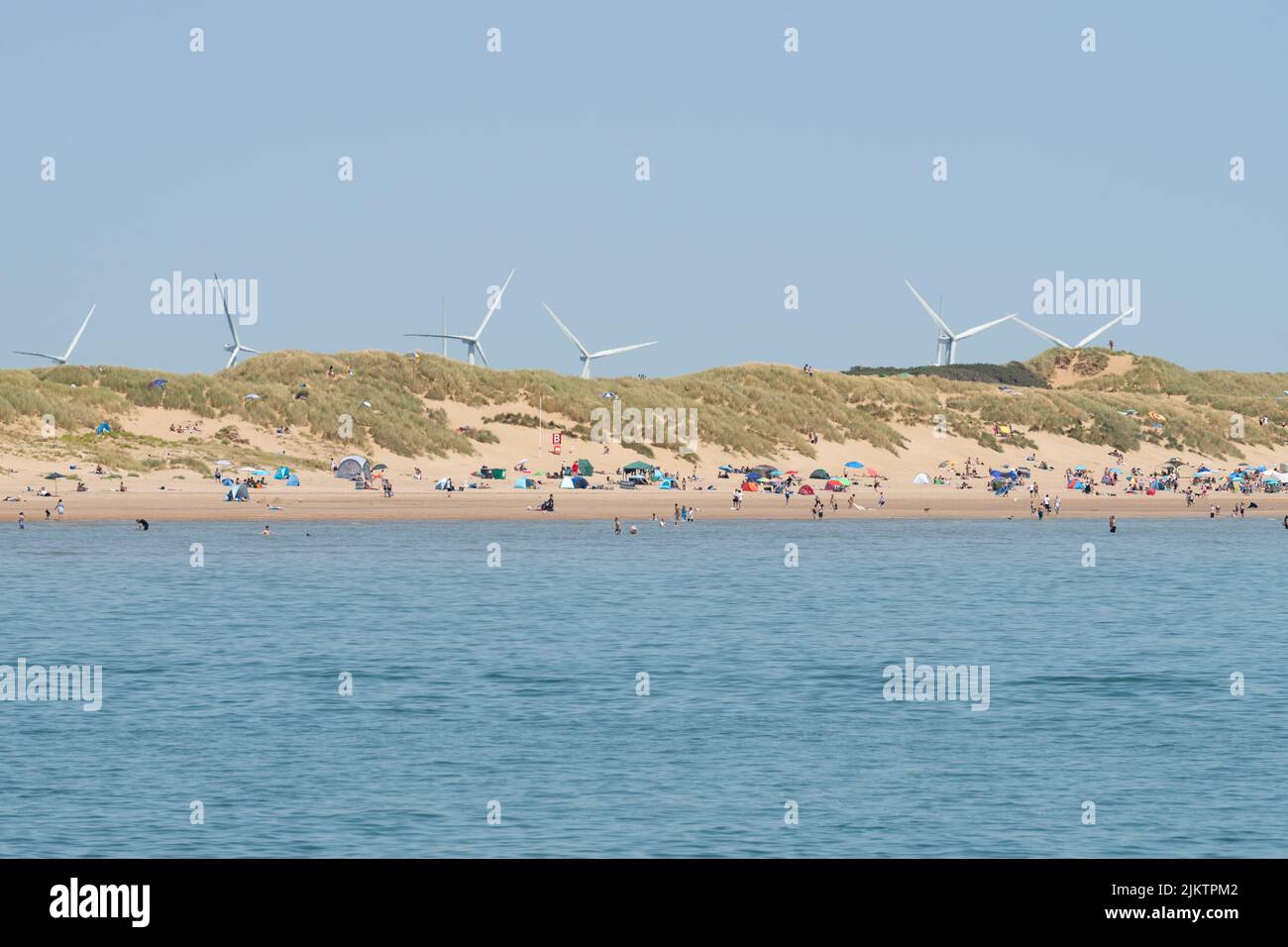 Parque eólico Little Cheyne Court - turbinas de viento visibles detrás de las dunas de arena en Camber Sands, East Sussex, Inglaterra, Reino Unido Foto de stock