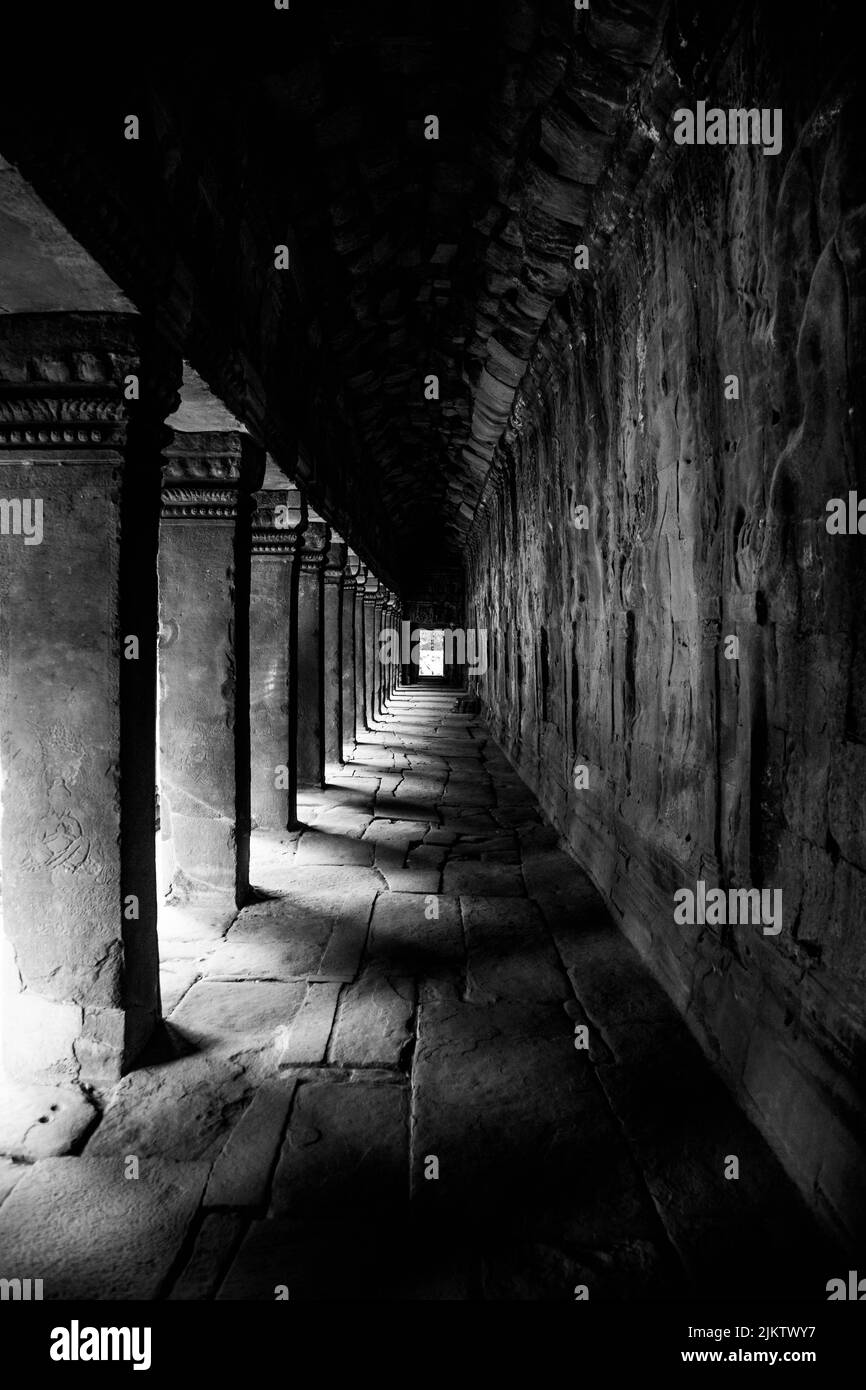 Una fotografía vertical en escala de grises de un callejón de piedra a través del templo de Angkor Wat en Camboya Foto de stock