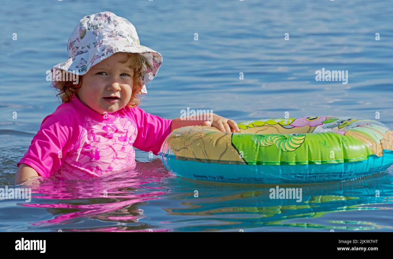 Niño jugando solo con un anillo de natación en el lago Foto de stock