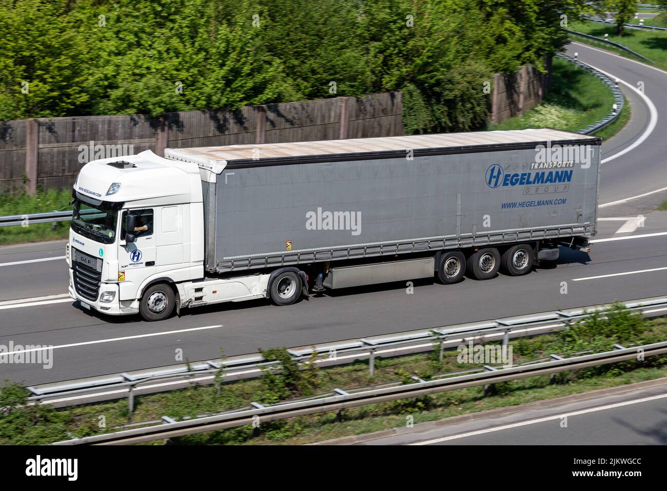Camión Hegelmann DAF XF con remolque lateral en autopista Foto de stock