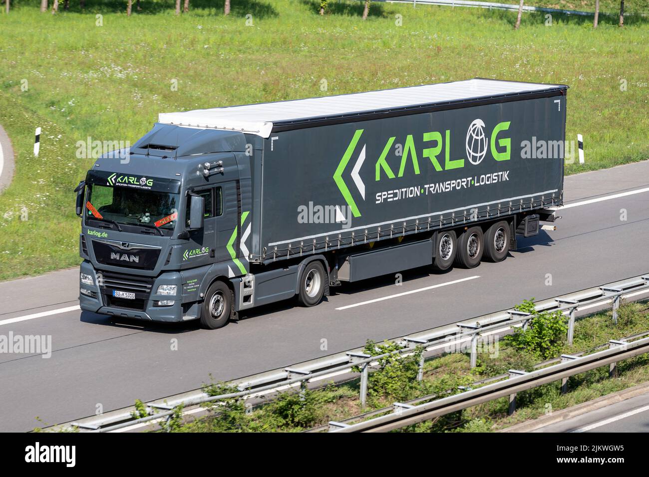 Camión KarLog MAN TGX con remolque lateral en autopista Foto de stock