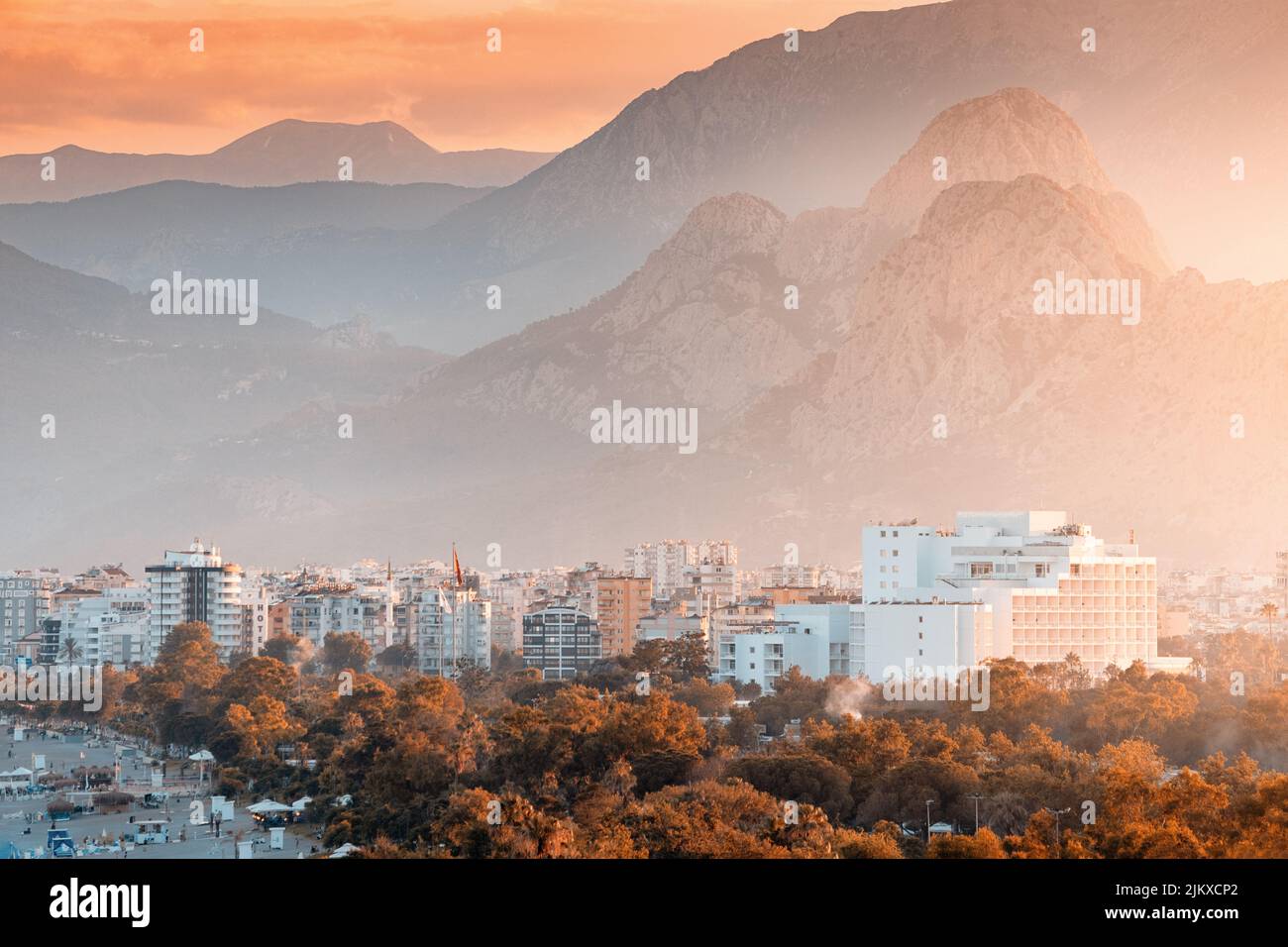Zoom distante vista del paisaje urbano de la ciudad turística de Antalya con hoteles y edificios y las montañas Tauro en el fondo Foto de stock