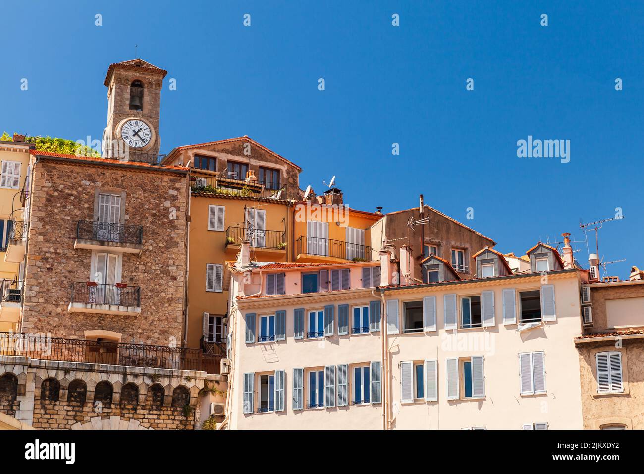 Cannes, Francia. Vista de la calle con casas residenciales antiguas y el campanario de la iglesia de Nuestra Señora de la Esperanza en un fondo Foto de stock