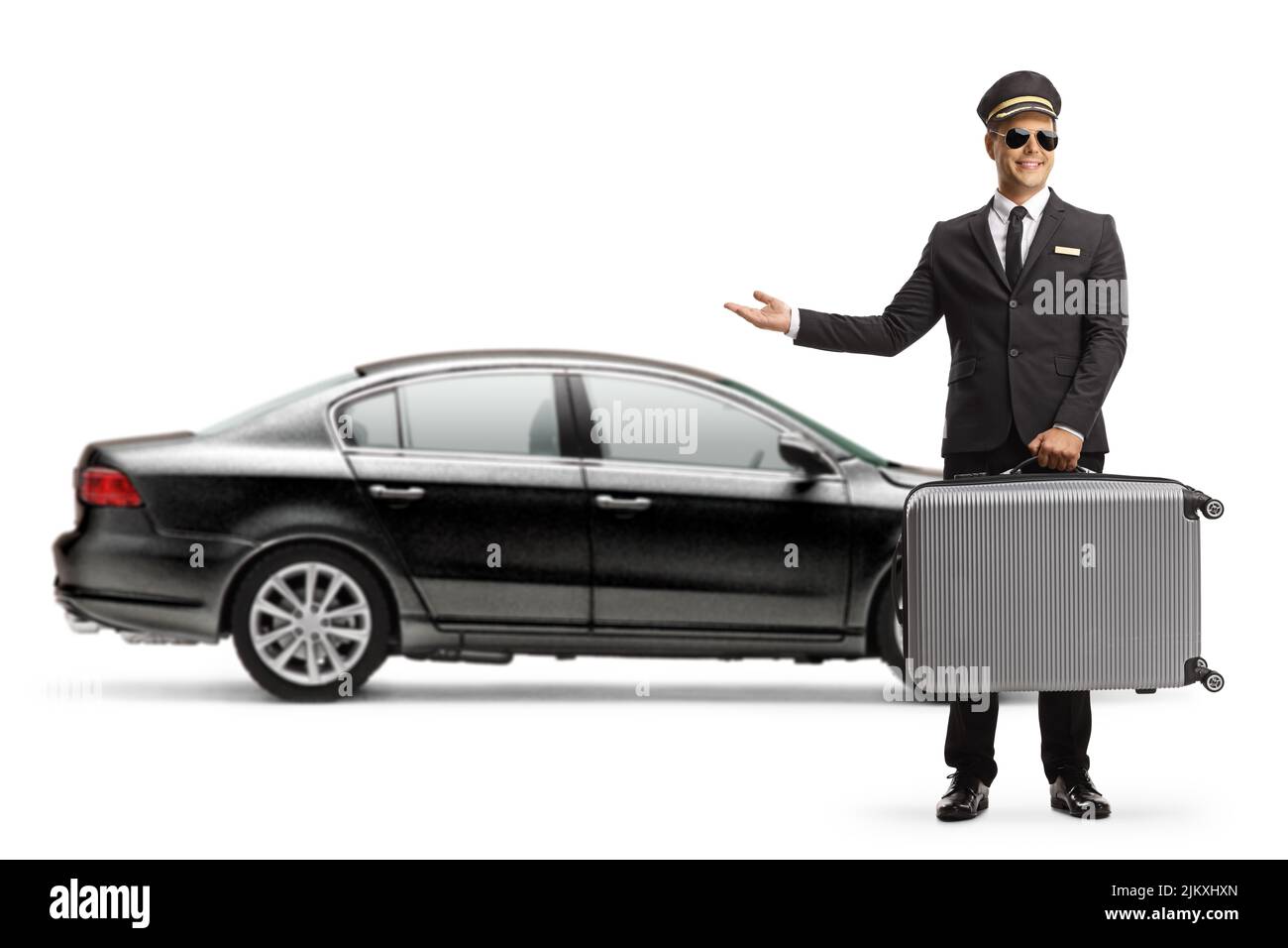Conductor llevando una maleta y señalando a un coche negro con la mano aislada sobre fondo blanco Foto de stock