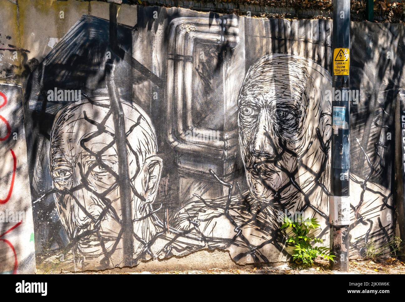 Arte callejero, mural de Canavar que representa a dos hombres detrás de una valla en Moda, Kadiköy distrito de Estambul, Turquía Foto de stock