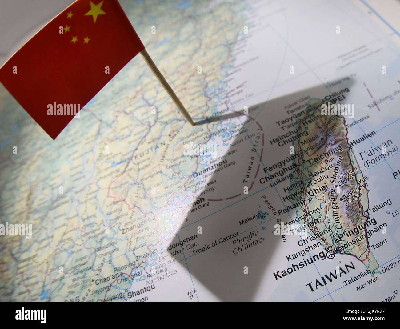 Un gráfico de estilo editorial que muestra la bandera china en un mapa que arroja una sombra desde su territorio sobre Taiwán y el disputado Estrecho de Taiwán. Foto de stock