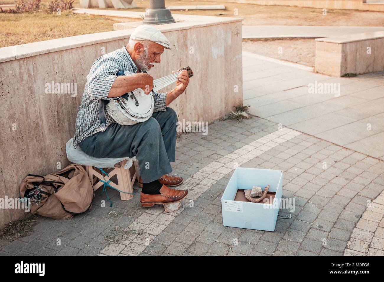 21 de junio de 2022, Antalya, Turquía: Hombre mayor tocando en el tradicional instrumento musical popular - saz y rogando por dinero en la calle de la ciudad Foto de stock