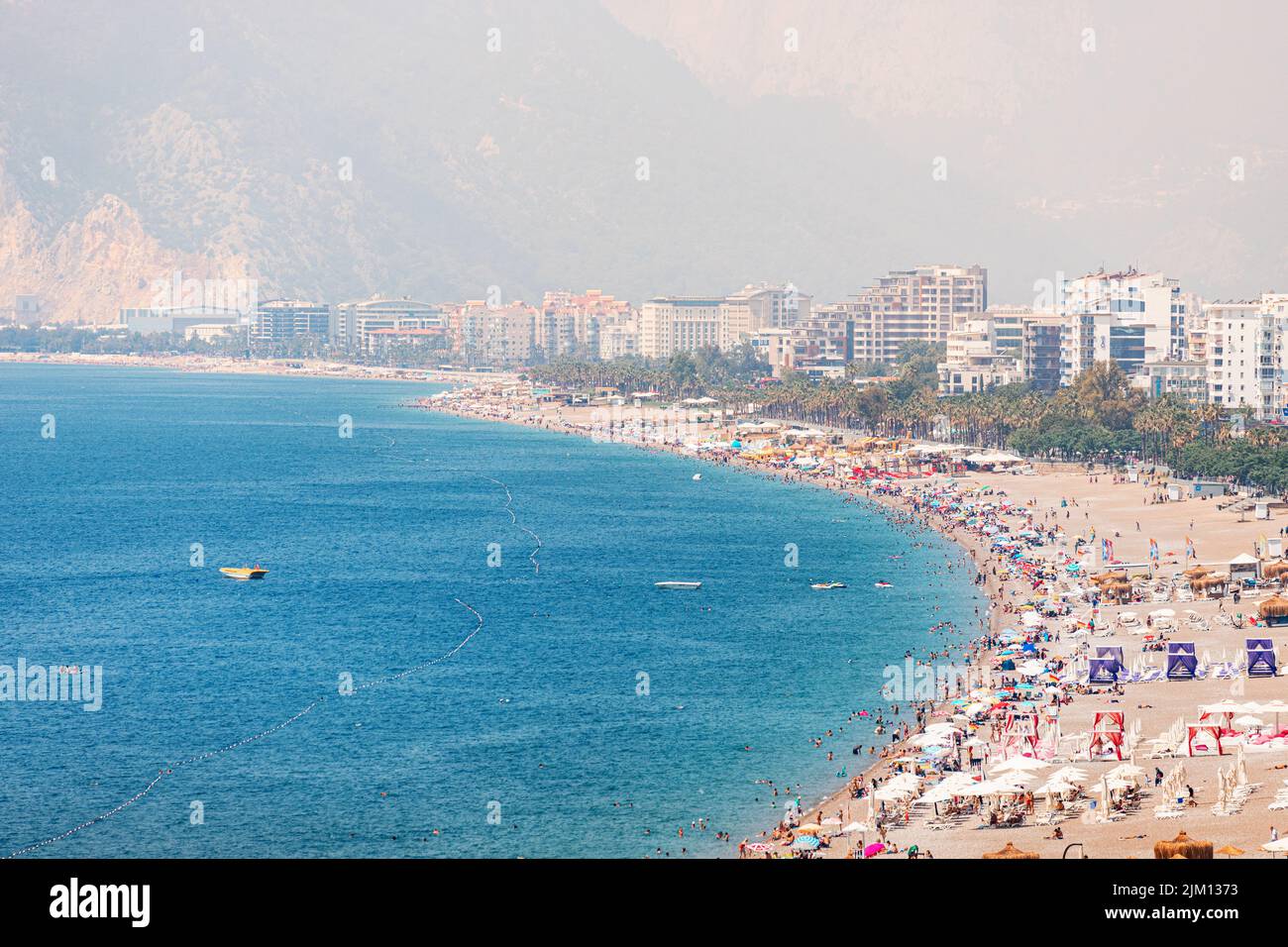 04 de junio de 2022, Antalya, Turquía: Playa de ciudad llena de gente con cientos de turistas y turistas descansando, tomando el sol y nadando en el verano extremadamente caliente d Foto de stock