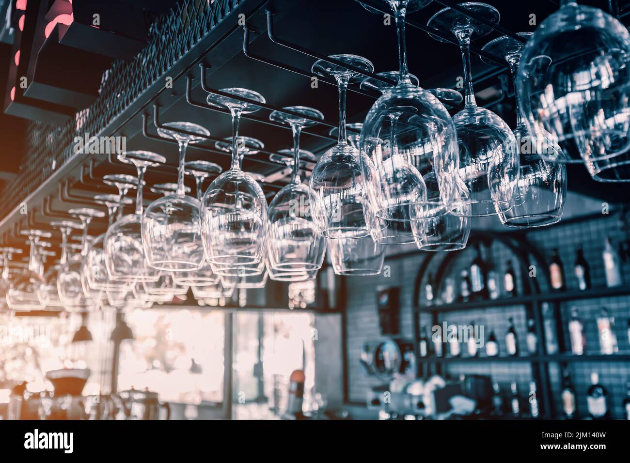 Copas de vino colgando y secando en bar de discoteca o restaurante con interior oscuro. Concepto de cóctel de alcohol Foto de stock
