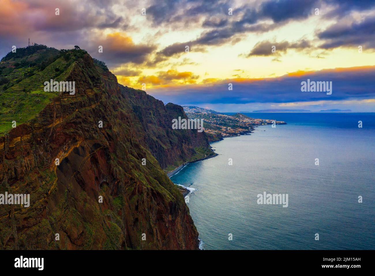 Puesta de sol sobre los acantilados de la isla de Madeira con la ciudad de Funchal en el fondo Foto de stock
