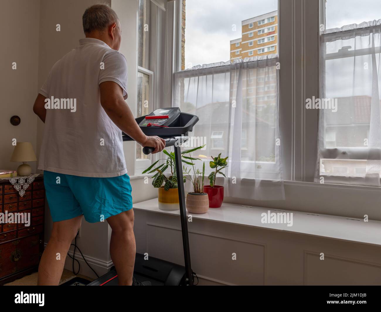 Un hombre mayor tratando de mantenerse en forma trabajando en una rueda de ardilla en casa. Foto de stock