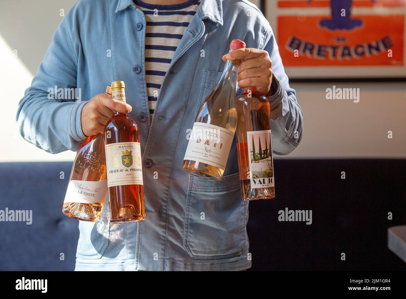 joven sosteniendo botellas de vino rosado en el interior Foto de stock