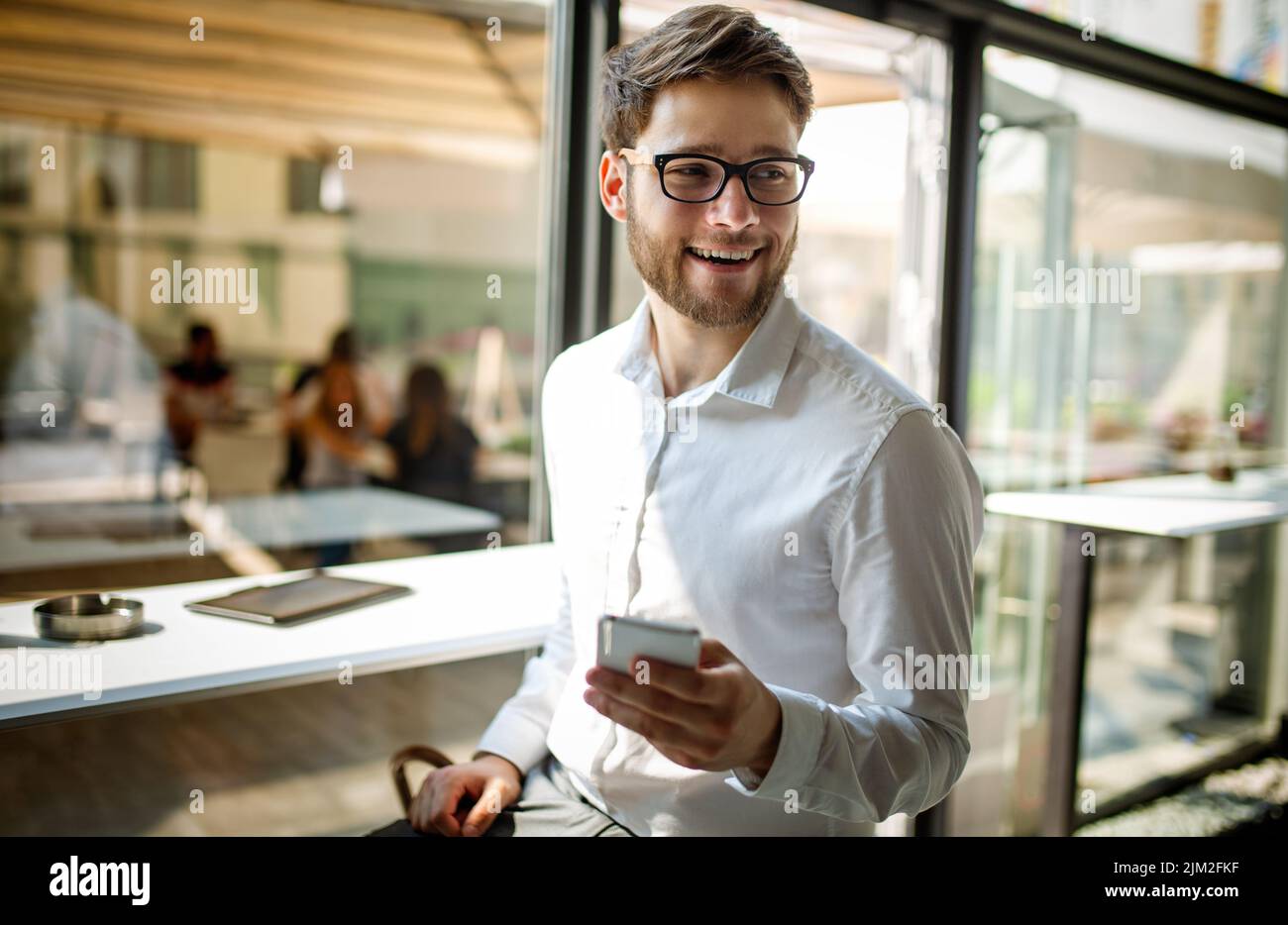 Joven hombre de negocios tomando café y haciendo su trabajo en el café. Personas, éxito, concepto de trabajo. Foto de stock