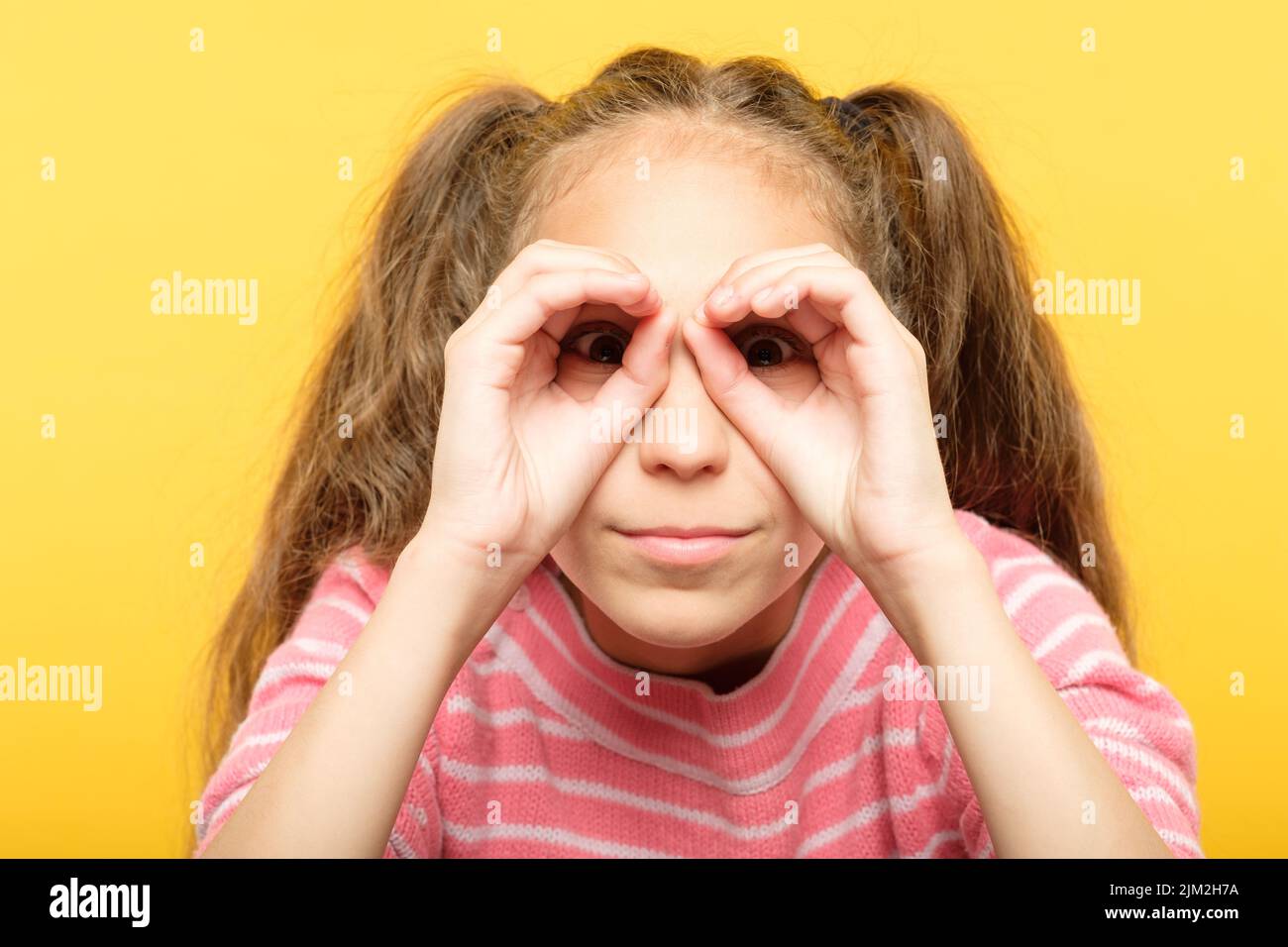 chica que pretende mirar binoculares manos búsqueda Foto de stock