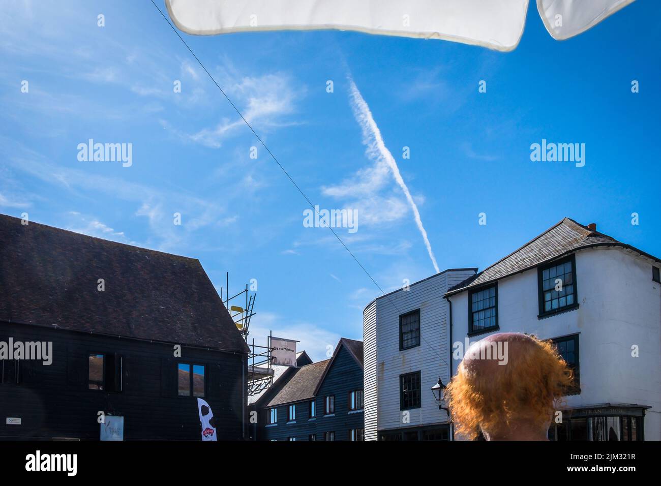 East Sussex, Inglaterra, 2022 de julio, primer plano de la cabeza de un hombre con pelo naranja bajo una sombrilla. Foto de stock