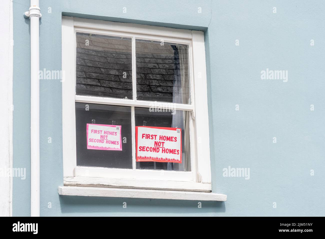 Los primeros hogares no los segundos aviso de los hogares exhibidos en la ventana delantera de la vieja casa en Lostwithiel, Cornwall en referencia a los dueños segundos caseros de Cornwall. Foto de stock
