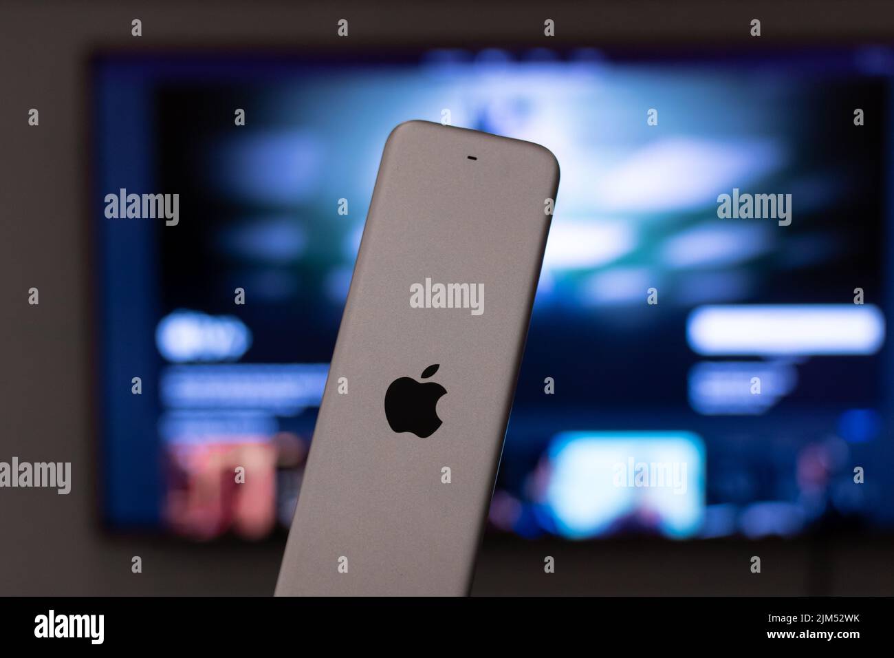El logotipo de Apple se ve en la parte posterior de un mando a distancia de AppleTV en un salón, con AppleTV+ en segundo plano. Foto de stock