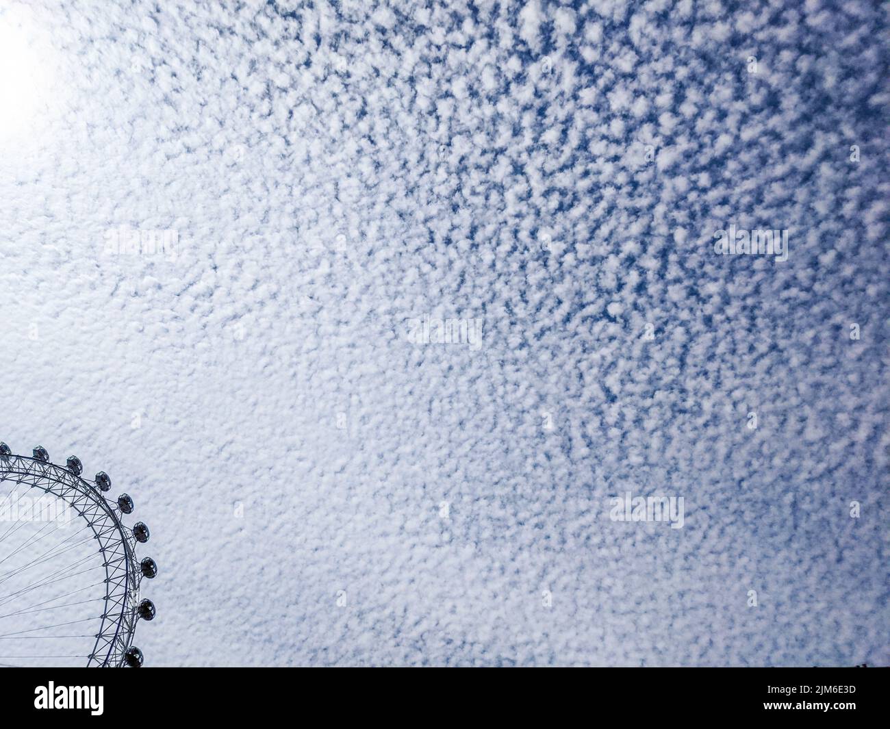 Una vista fascinante de las ruedas de los Ferris del ojo de Londres contra el cielo azul brillante con las nubes frescas Foto de stock