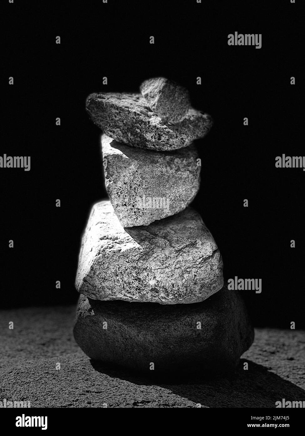Una fotografía en escala de grises de piedras apiladas sobre una enorme roca junto al lago Foto de stock