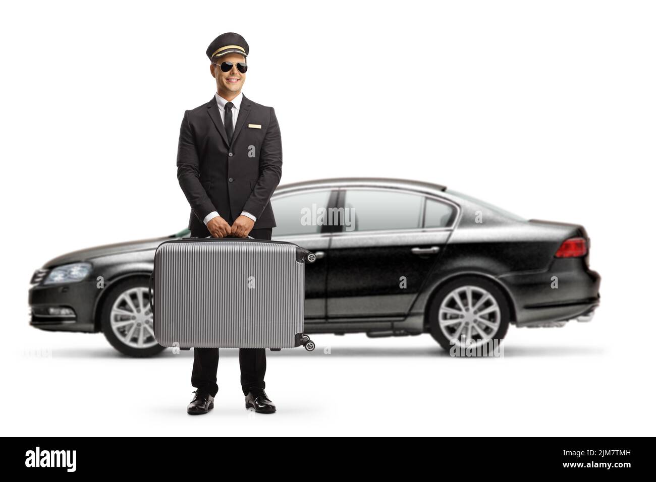 Chofer que lleva una maleta y que está de pie frente a un coche negro aislado sobre fondo blanco Foto de stock