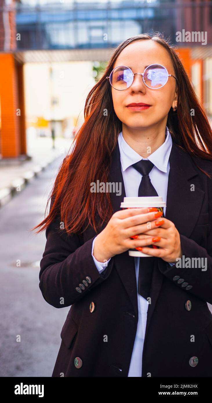 Sonriente empresaria bebiendo café para ir a la calle Foto de stock