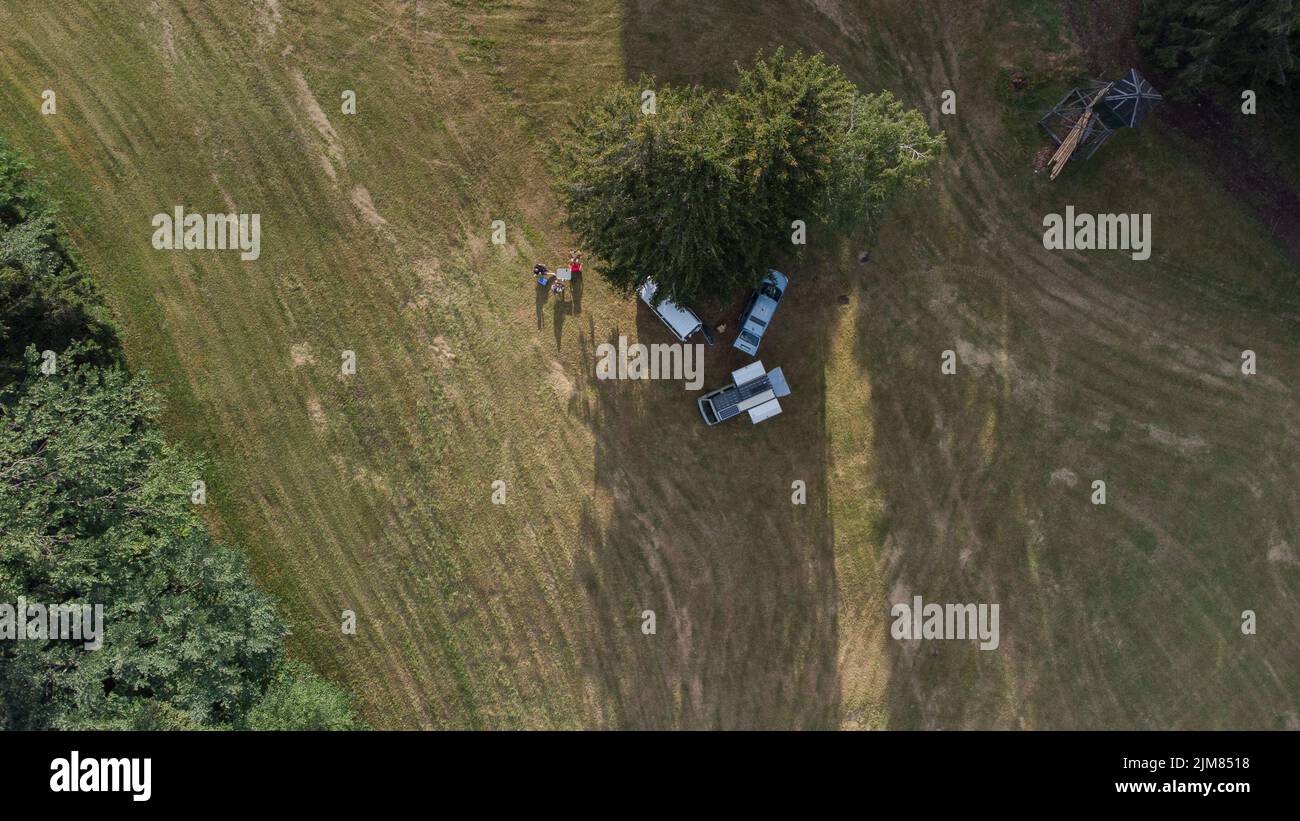 Camping salvaje con equipo de camioneta o camioneta RV. Vista vertical aérea de un campamento de vida en furgoneta. Estilo Vanlife, tres camiones estacionados junto a un árbol con campistas Foto de stock
