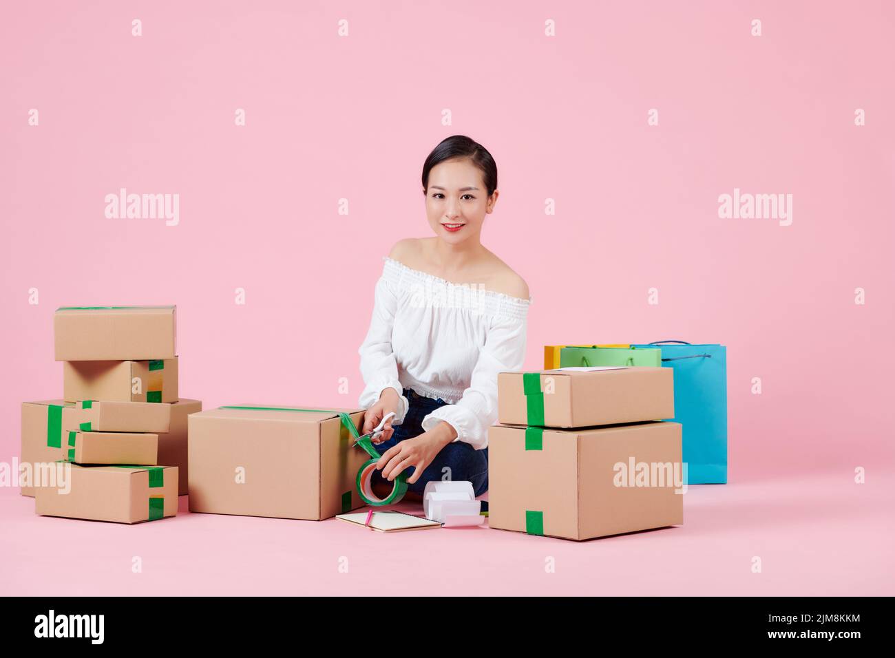 Mujer asiática embalaje de mercancías con cinta adhesiva para la venta en línea, concepto de entrega. Foto de stock