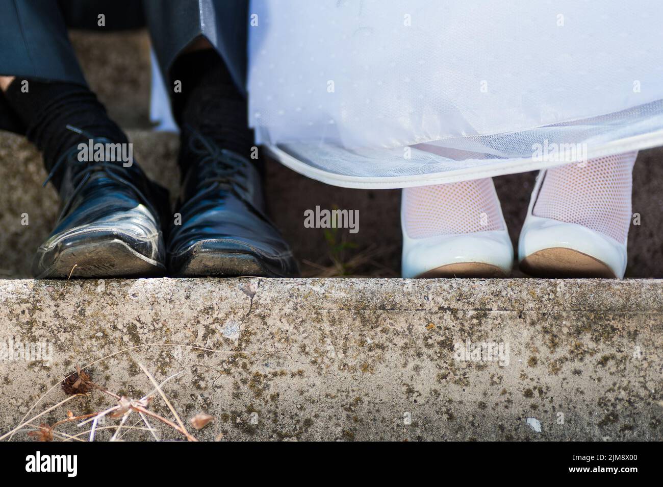 La novia y el novio en zapatos usados de la boda. La pareja del resto Foto de stock