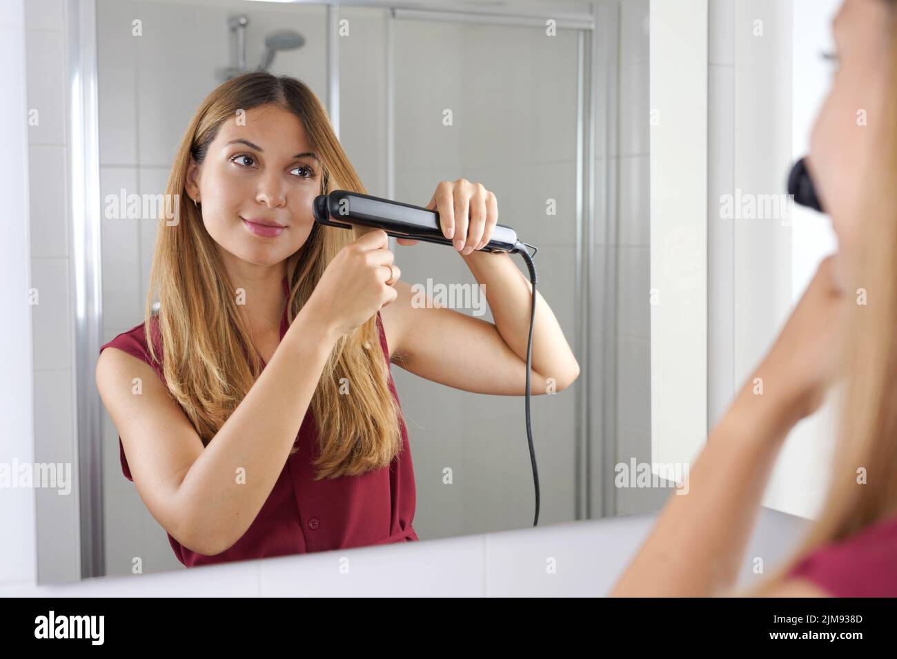 Mujer joven hermosa usando Streapod para alisar el pelo de una manera fácil en el hogar Foto de stock