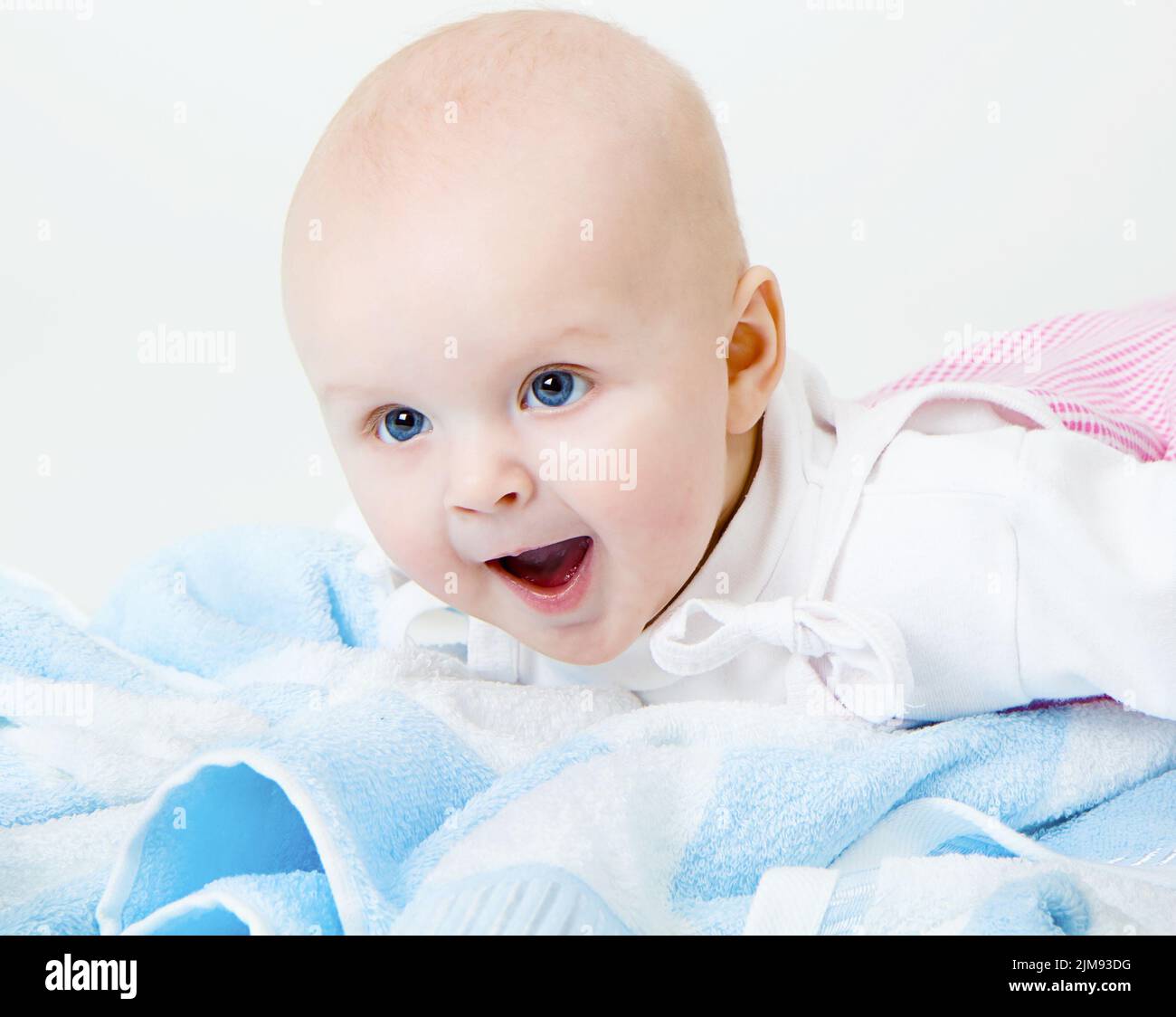 niña feliz llorando sobre una toalla azul Foto de stock