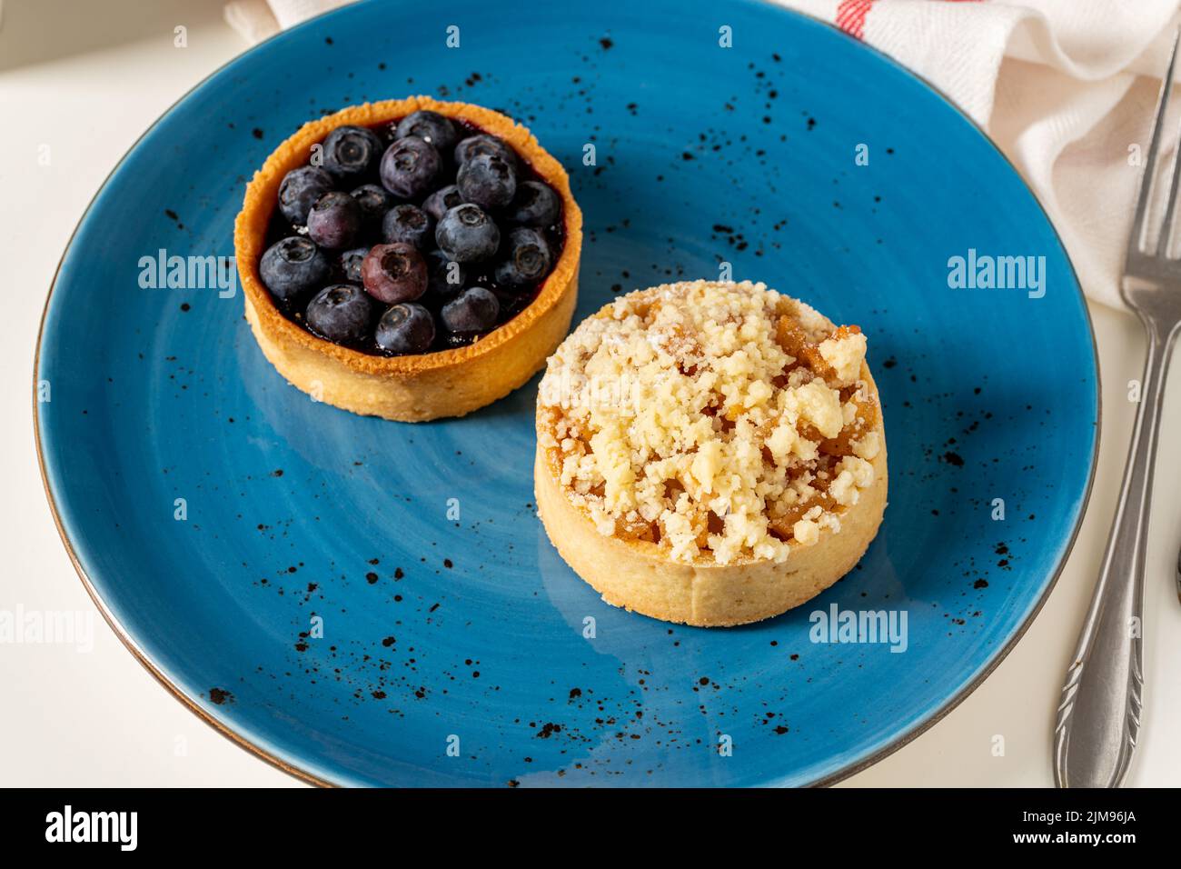 Una porción recién horneada de pastel de arándanos y manzana en un plato de porcelana azul Foto de stock