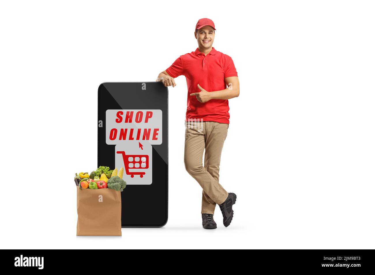Mensajero apoyado en un teléfono móvil grande con tienda de texto en línea y una bolsa de alimentación y apuntando aislado sobre fondo blanco Foto de stock