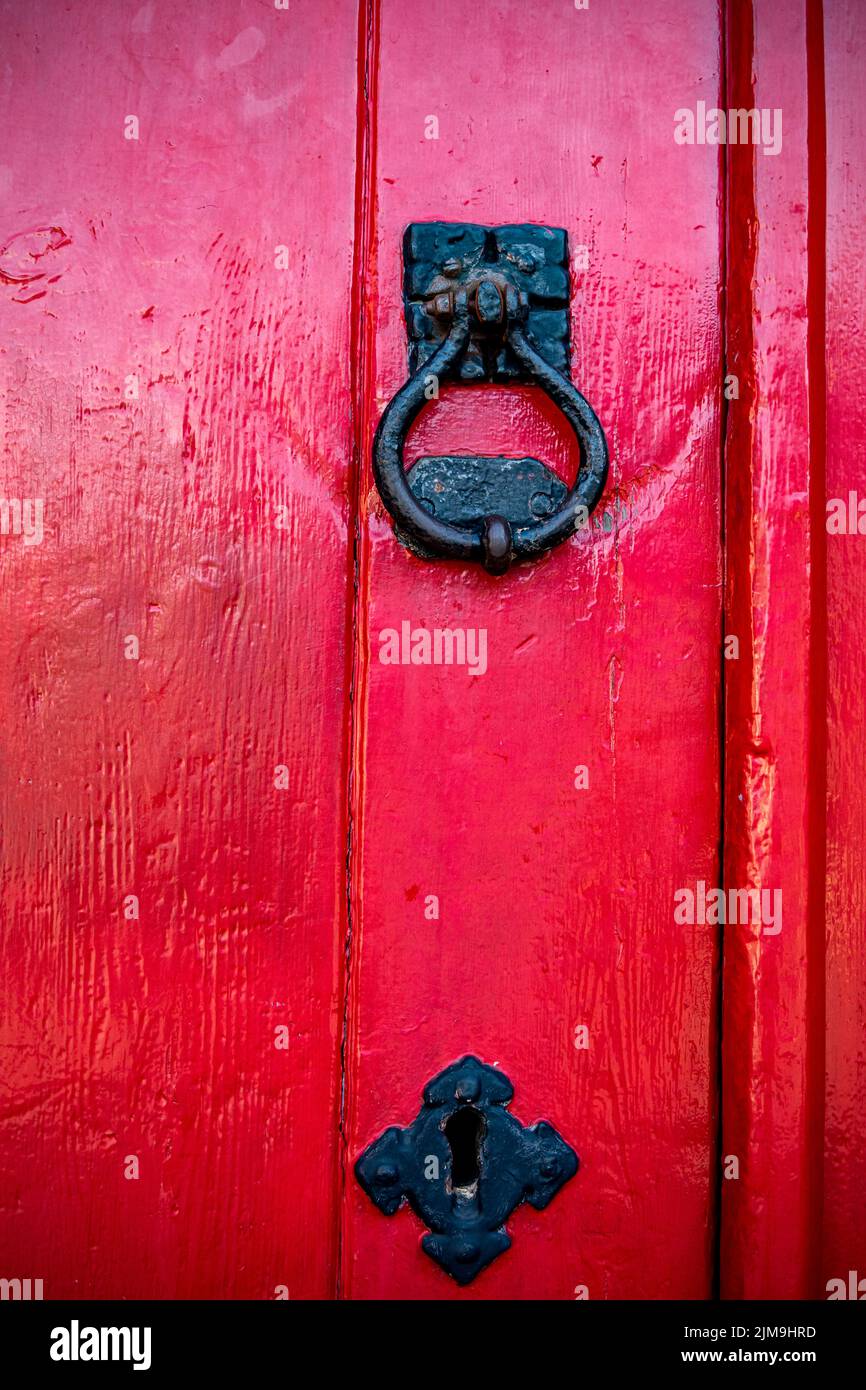 Detalle de una puerta pintada de rojo con el atador de puerta Foto de stock