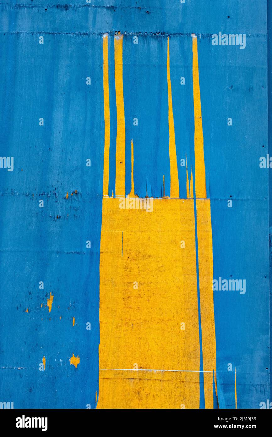 Pintura azul y amarilla astillada sobre panel de madera Foto de stock