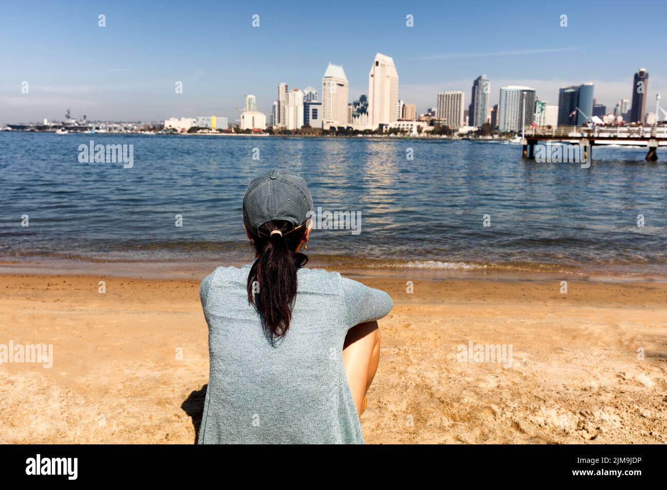 Mujer disfrutando de la vista de la bahía de San Diego y el horizonte mientras se sienta en la playa Foto de stock