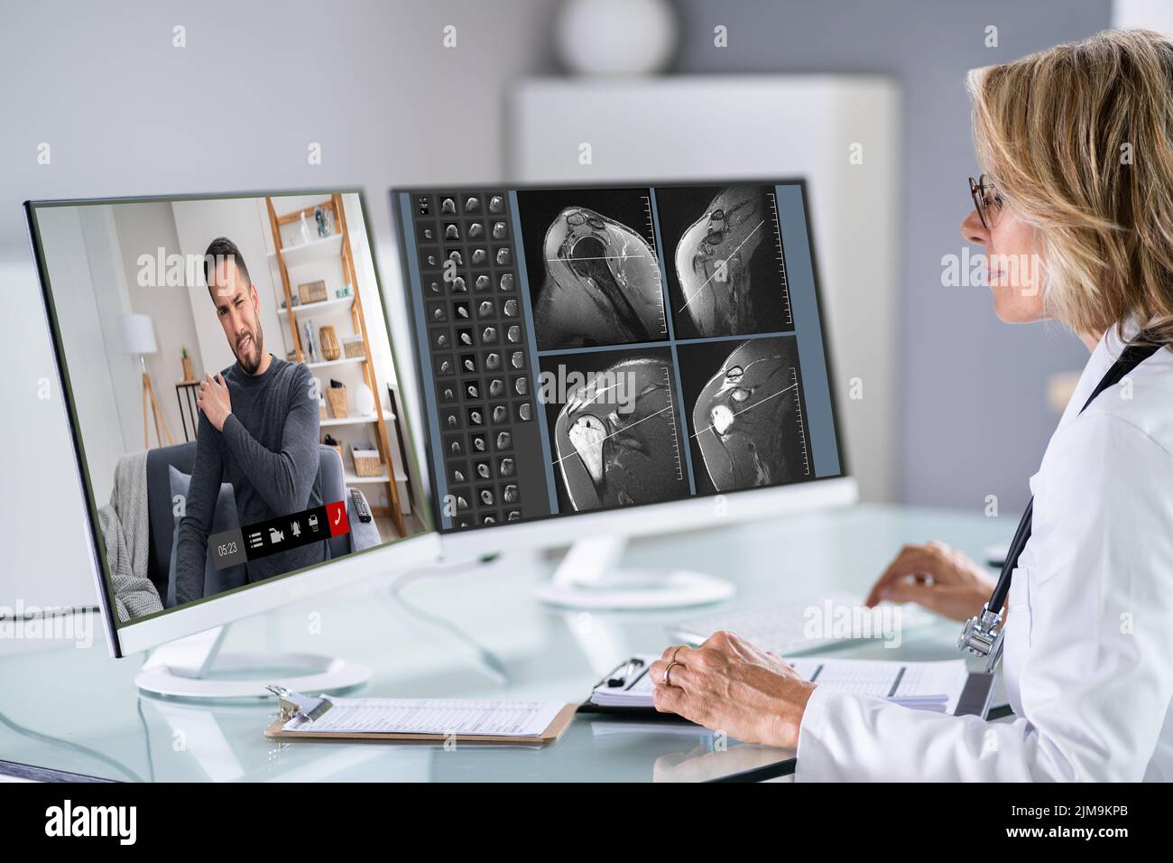 Videoconferencias en línea. Médico que mira a la exploración MRT del hombro caucásico Foto de stock