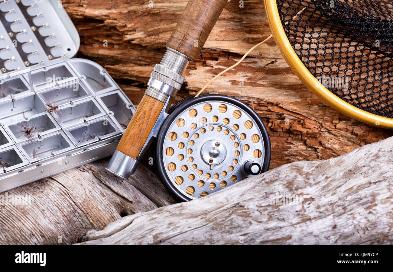 Equipo vintage de pesca con mosca y equipo sobre rocas y fondo de madera Foto de stock