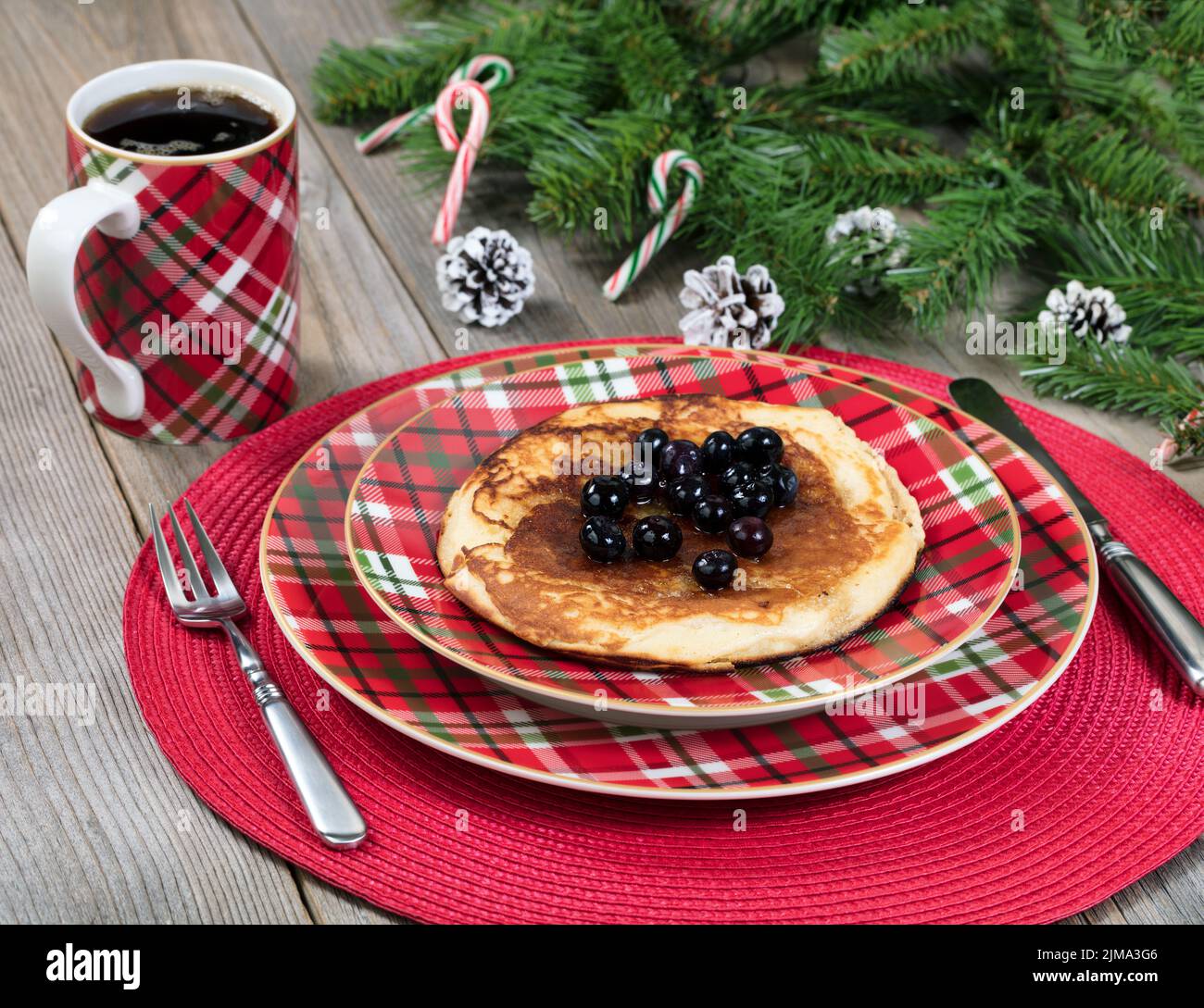 Desayuno de crepes para el día de Navidad con ramas de hoja perenne sobre rústicas tablas de madera Foto de stock