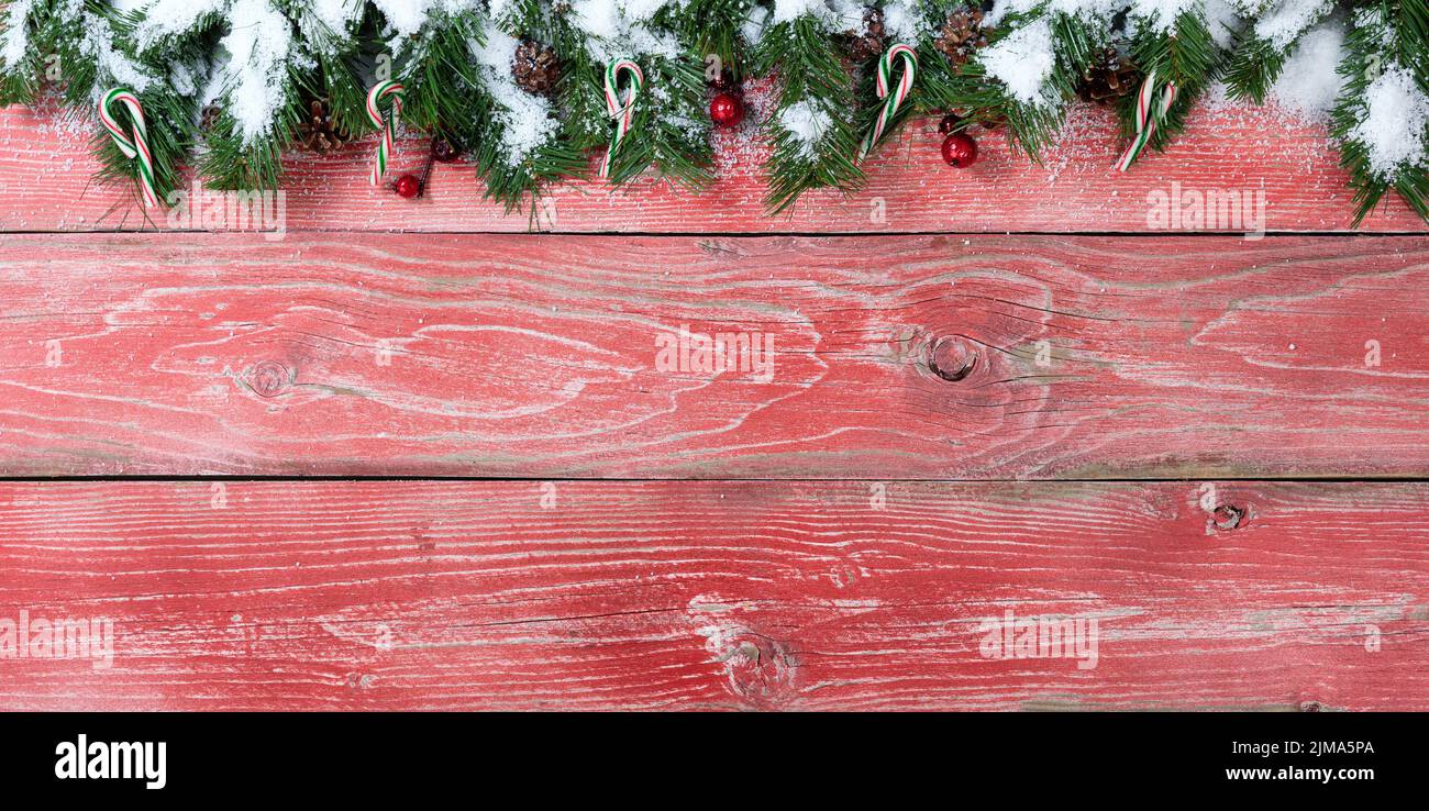 Rústicas tablas de madera roja con ramas de abeto nevado para el concepto de la temporada navideña Foto de stock