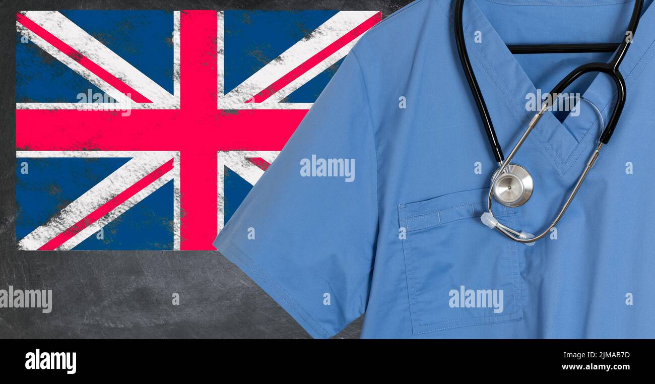 Médico friega la camisa azul y el estetoscopio colgando vacío delante de bandera británica. Ilustración de los médicos procedentes de otros países al personal natio Foto de stock