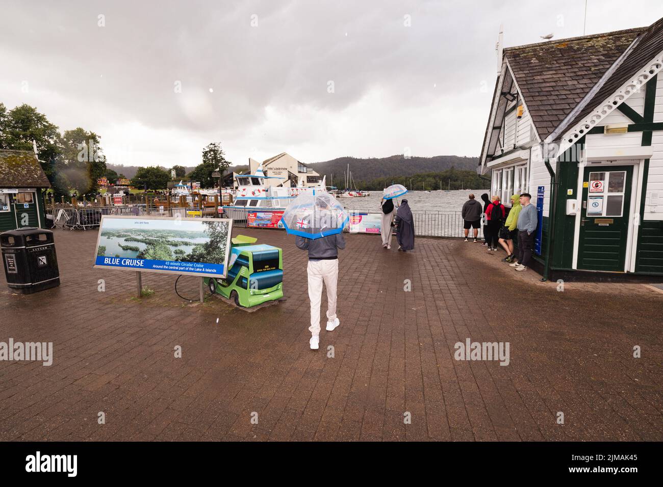Lake District Cumbria 5th de agosto de 2022 UK.UK Weather Lake Windermere. Fuerte ducha de lluvia por la tarde durante media hora, pero los visitantes estaban listos con sus impermeables, todavía disfrutan de sus vacaciones, Bowness Bay Prom y la playa. Crédito: Gordon Shoosmith/ Live News Foto de stock