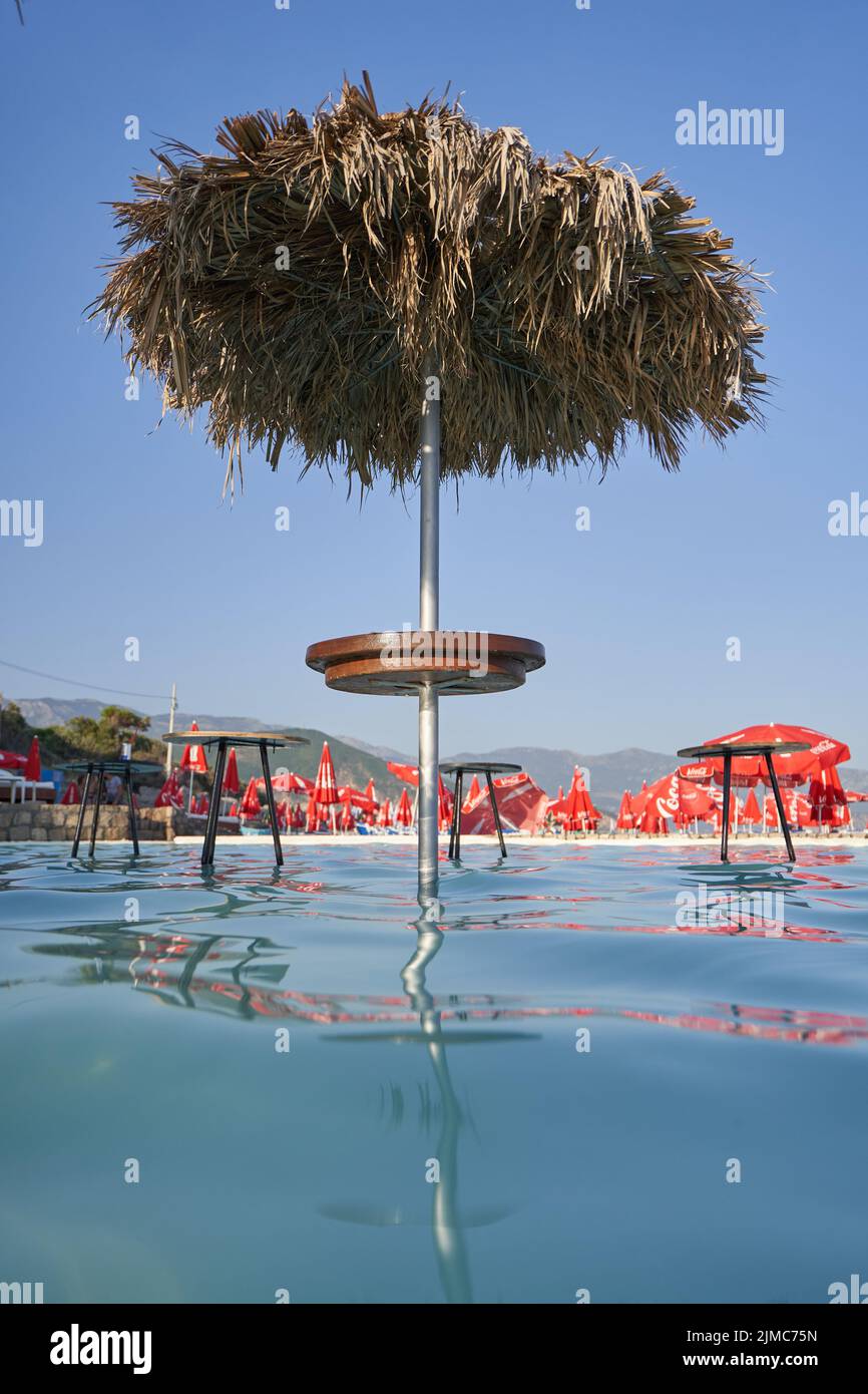 Sombrilla de sol hecha de hojas de palma en un lugar bar de playa en la piscina Foto de stock