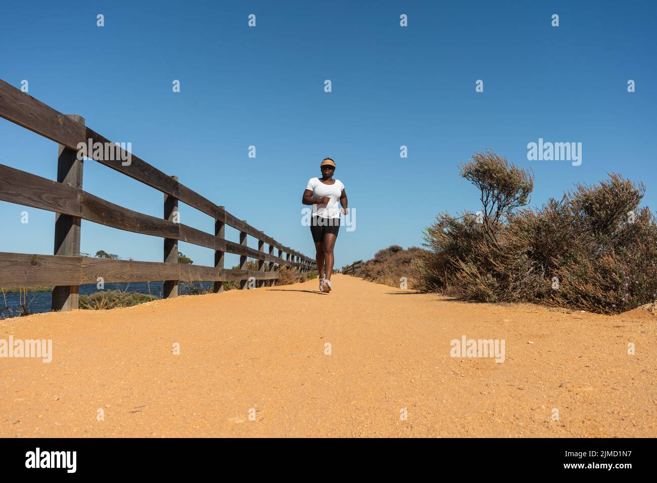 Mujer negra corriendo en la arena en un día caluroso Foto de stock