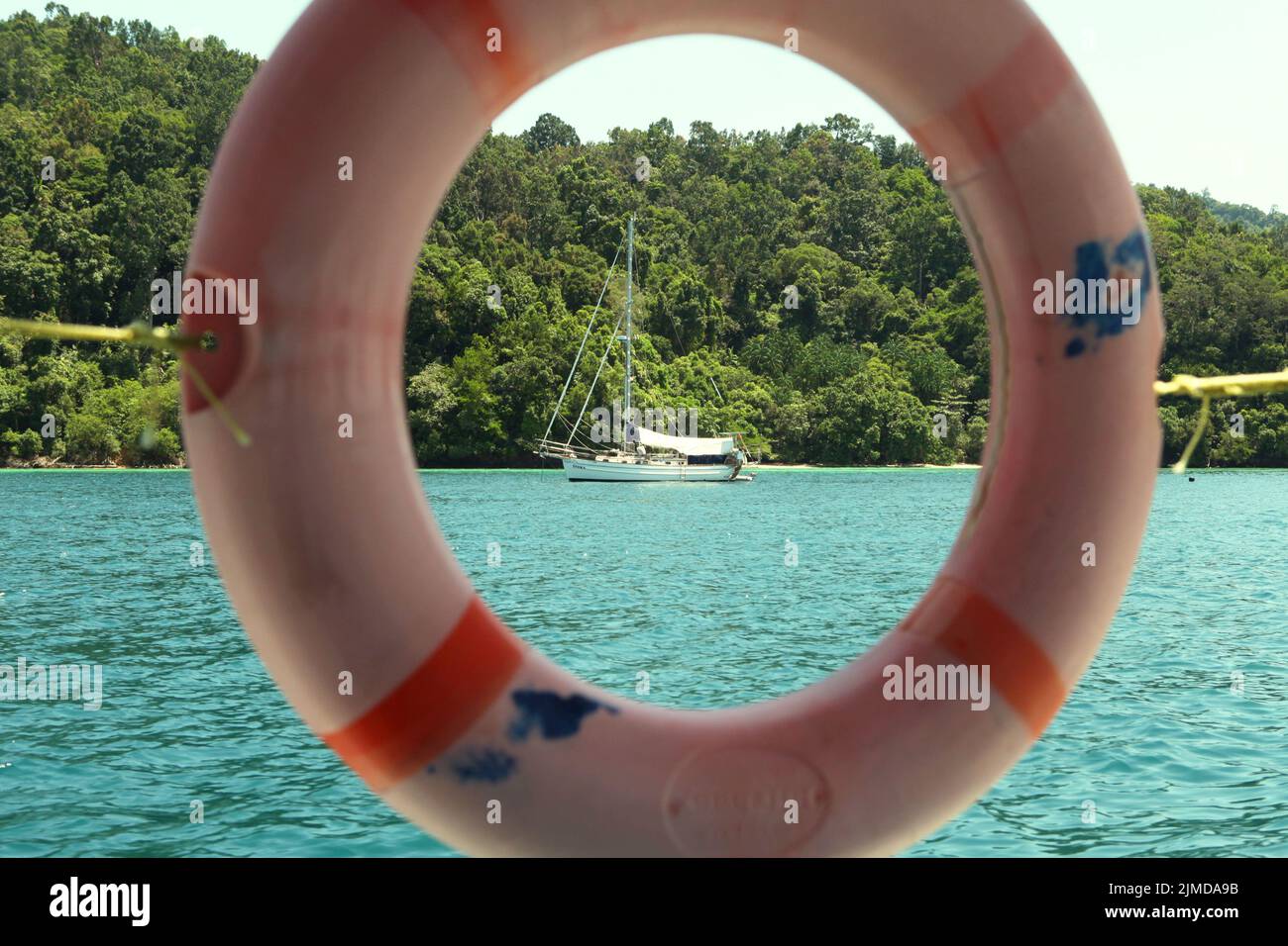 Se puede ver un barco turístico en las aguas costeras dentro del parque Tunku Abdul Rahman en Sabah, Malasia. Foto de stock