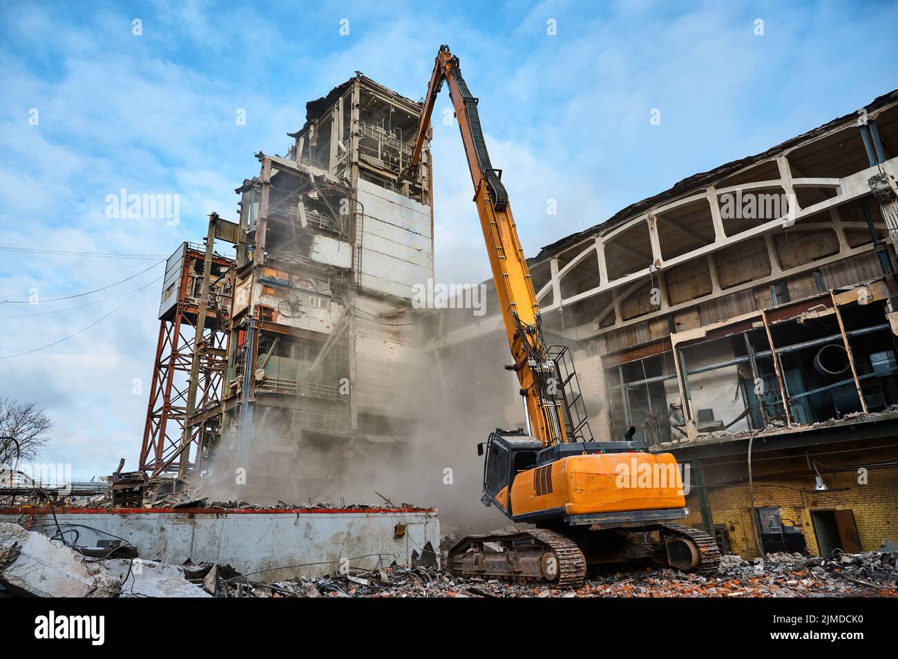 Demolición de un edificio industrial abandonado por excavadora Foto de stock