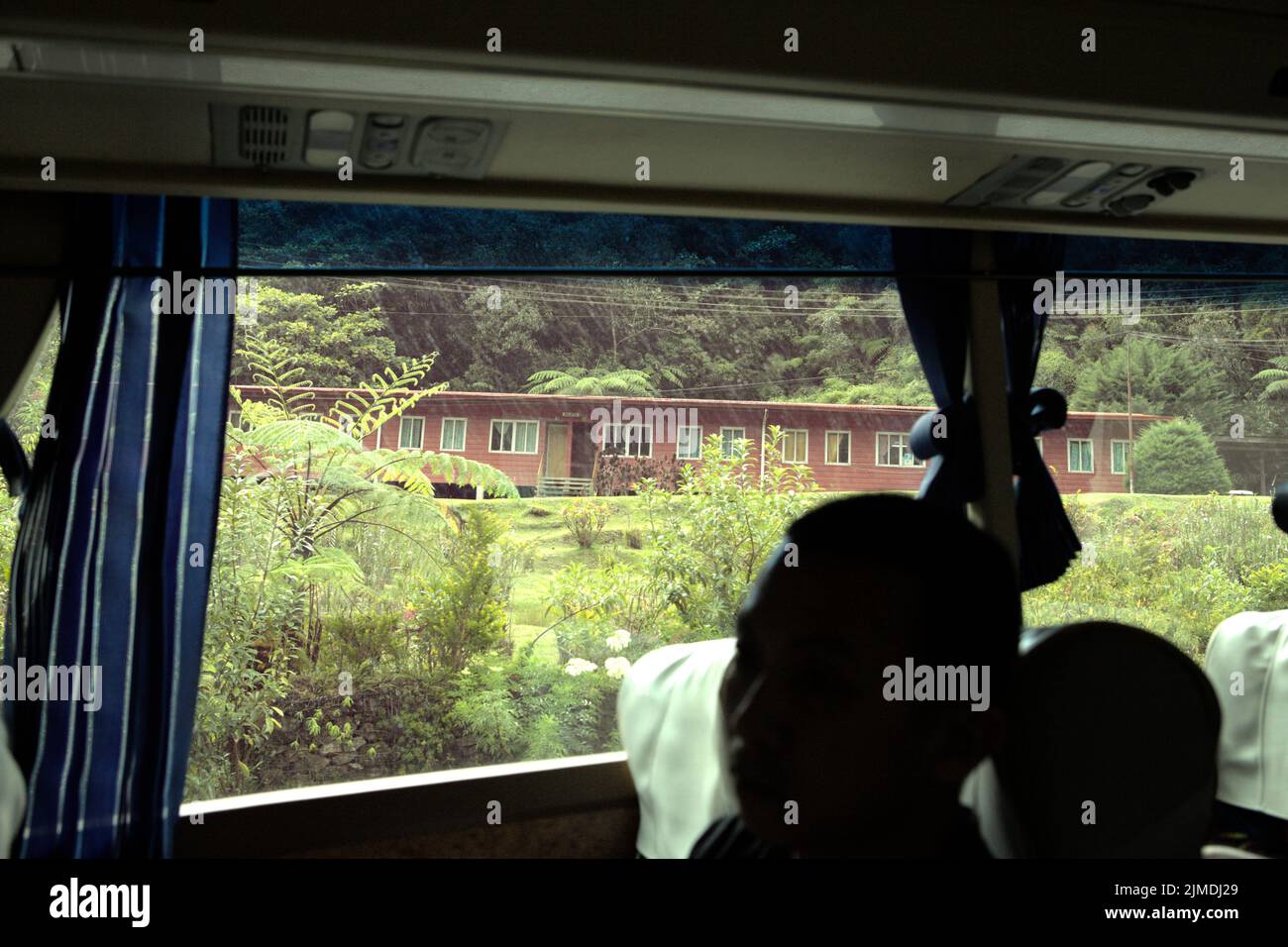 Un eco-lodge se ve desde dentro de un autobús que se mueve en una carretera en el Parque Kinabalu en Ranau, Sabah, Malasia. Foto de stock