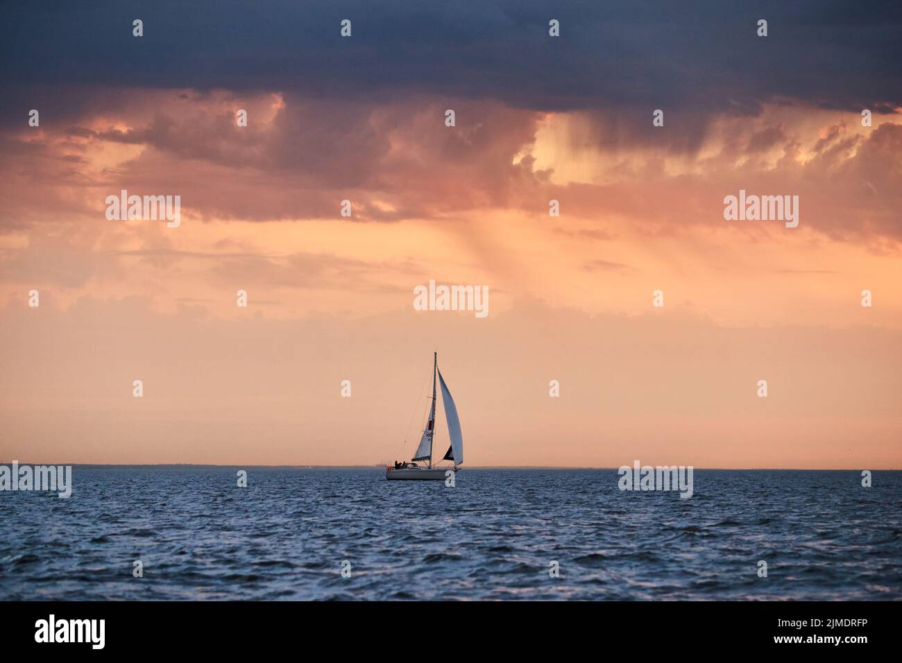 El solitario velero en una lista va por el mar, el cielo de color rosa, el cielo de tormenta Foto de stock