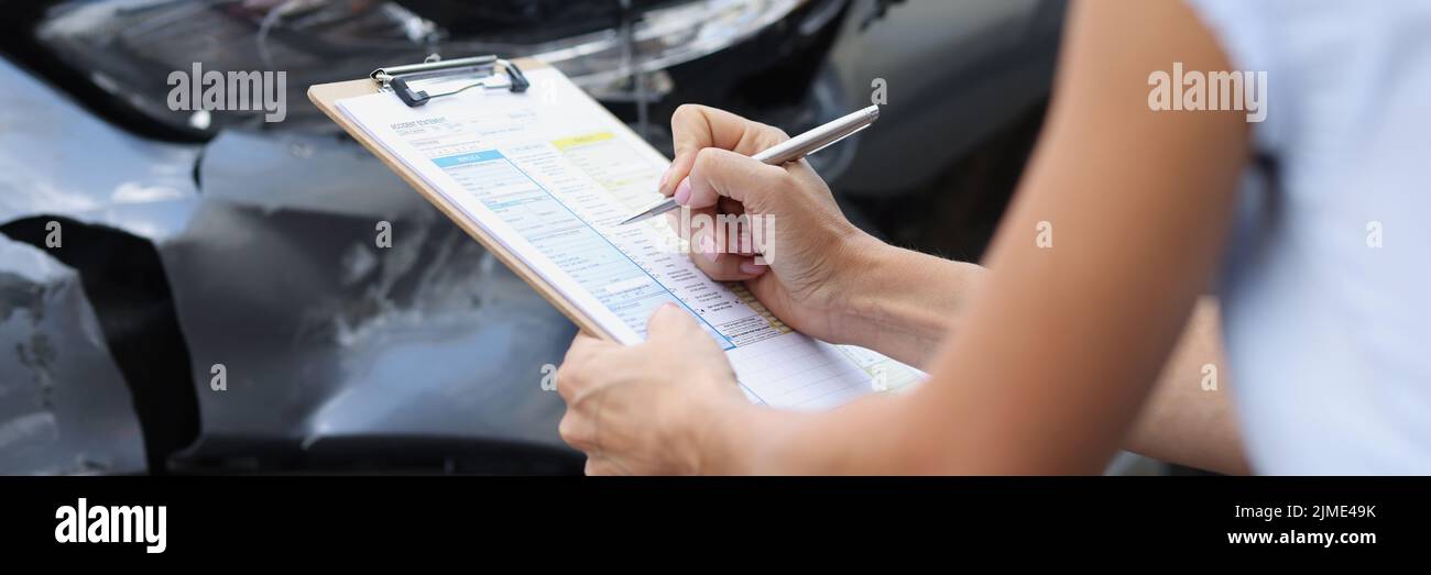 Una mujer en un coche roto llena un documento, borroso Foto de stock